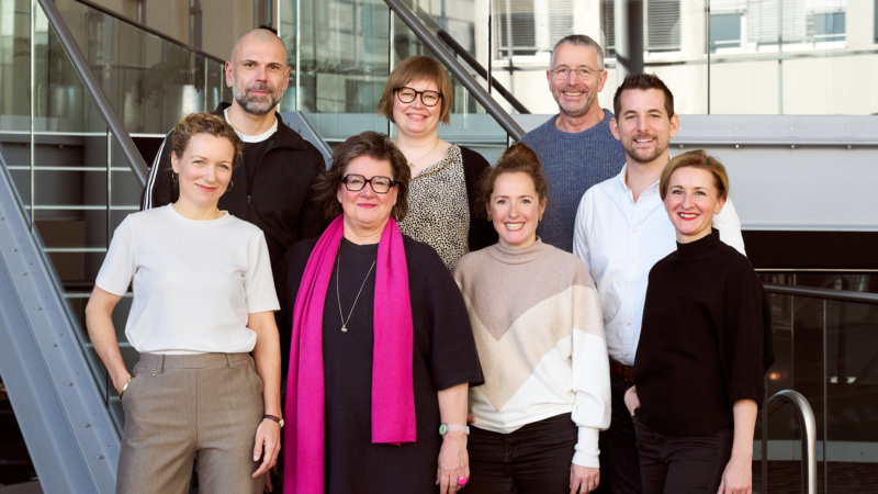 Menschen in zwei Reihen auf einer Treppe stehend, sie lächeln und freuen sich über ihre neuen Rollen