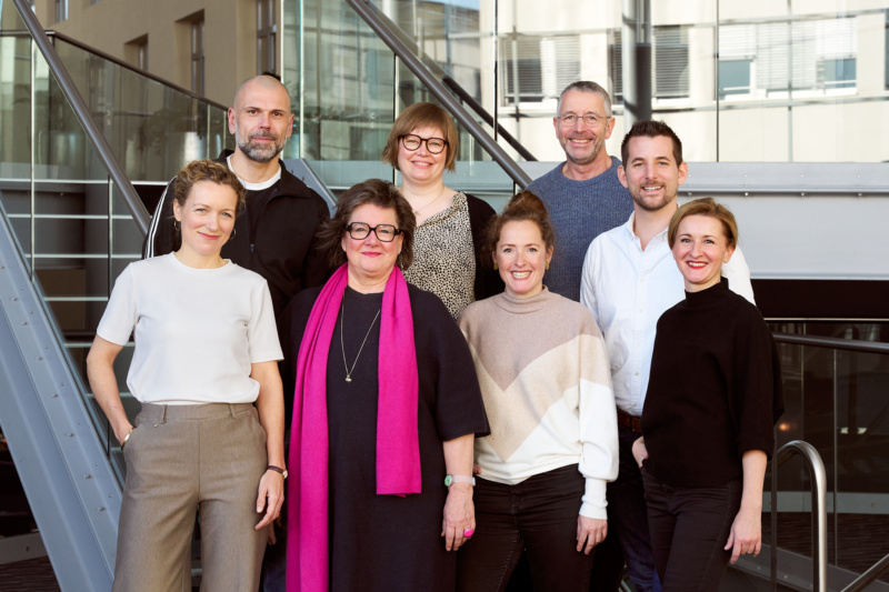 Menschen in zwei Reihen auf einer Treppe stehend, sie lächeln und freuen sich über ihre neuen Rollen